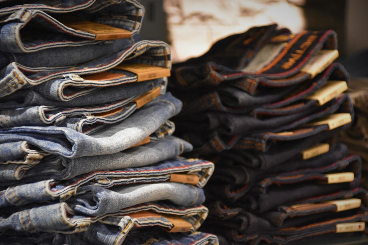 services-04 Close-up of folded denim jeans stacked in a retail store setting.