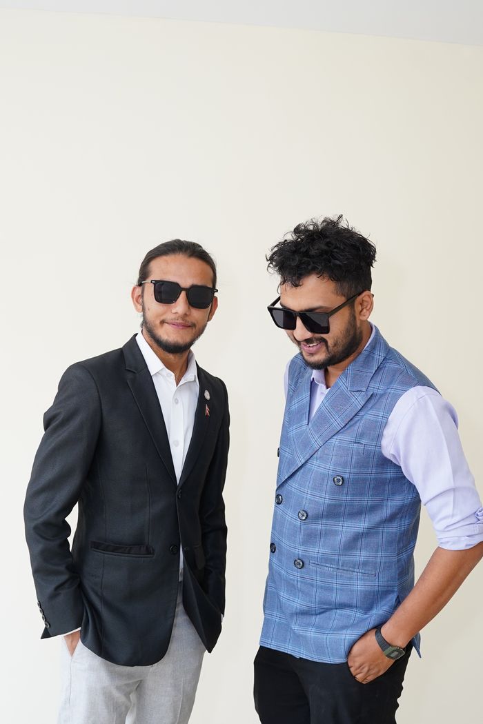 services-02 Two stylish men wearing sunglasses pose confidently in a studio shoot.