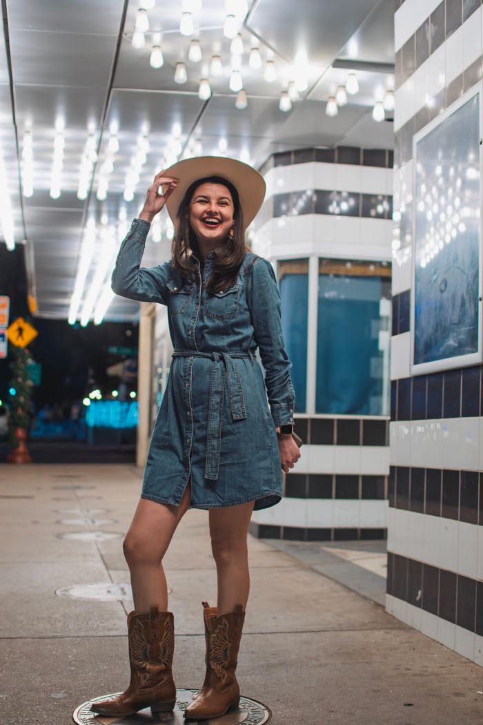 Crafting Captivating Headlines: Your awesome post title goes here Woman in cowboy attire smiling outdoors at night in Fort Worth.